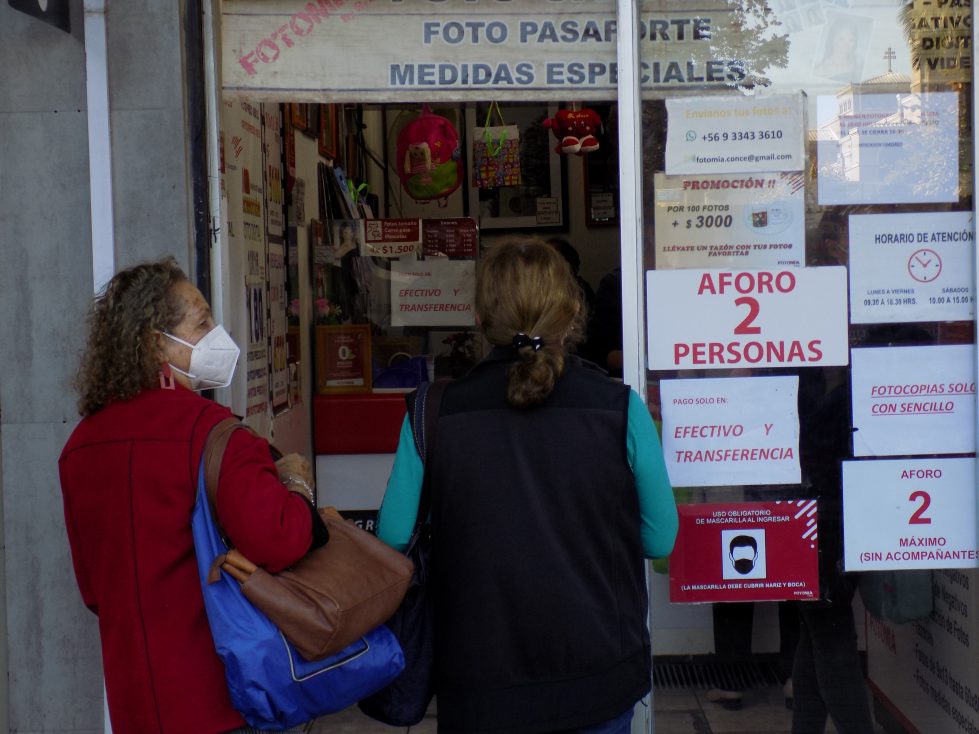 Dos mujeres esperan afuera de una tienda de fotografías en el centro de Concepción.